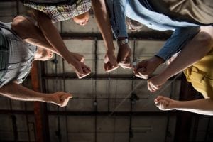 View from floor of four bodies hold fists in semi-circle